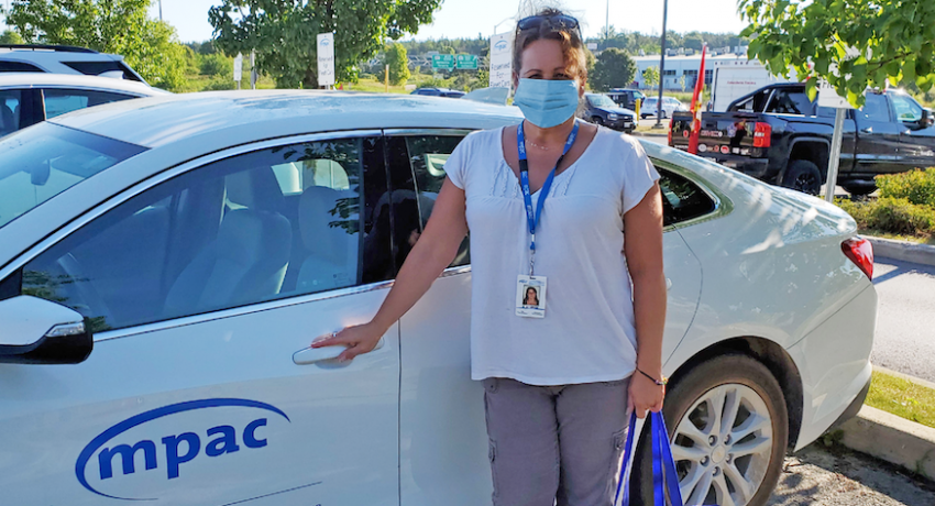 Woman wearing surgical mask standing beside MPAC vehicle