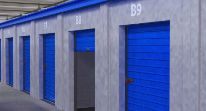 Blue doors to storage units line a hallway of an enclosed self-storage facility.
