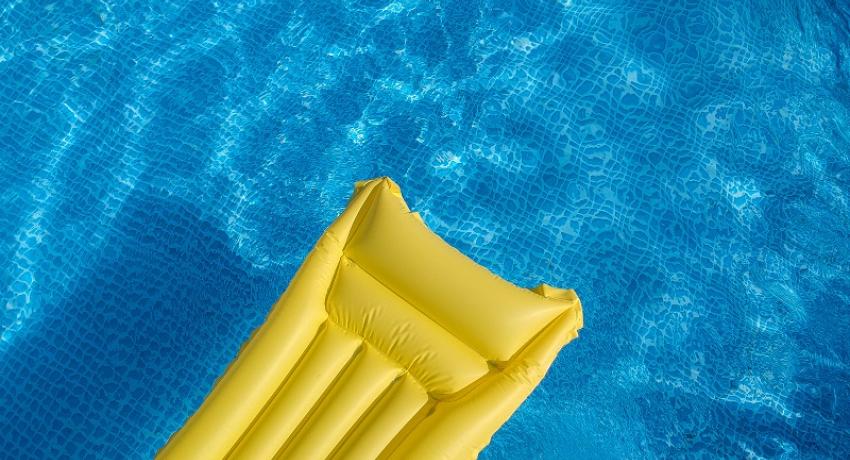 Yellow inflatable pool lounger floating in a pool